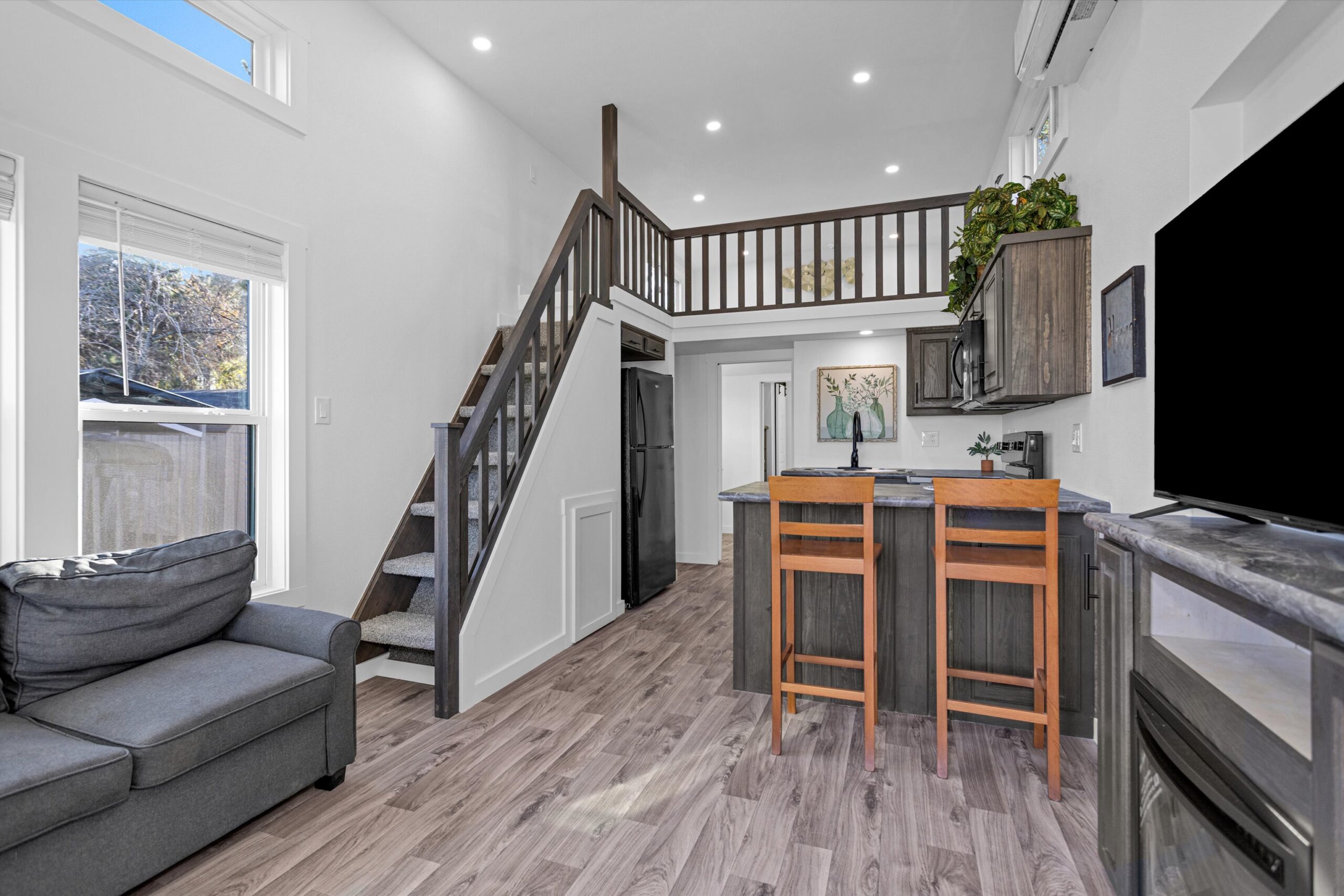 Interior view of Barn Owl by Platinum tiny home showing loft stairs leading down to the main living area