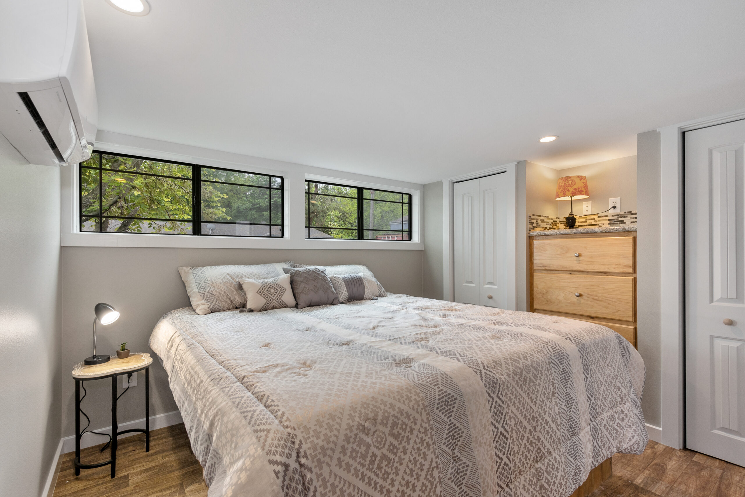 Master bedroom inside Big Blue Master tiny home with built-in storage and natural light